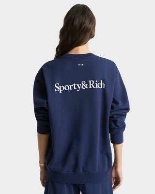 Person wearing a navy blue sweatshirt with 'Sporty&Rich' logo on the back against a light gray background