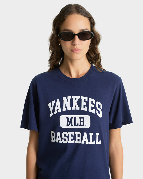 Person wearing a navy blue 'Yankees MLB Baseball' t-shirt on a white background
