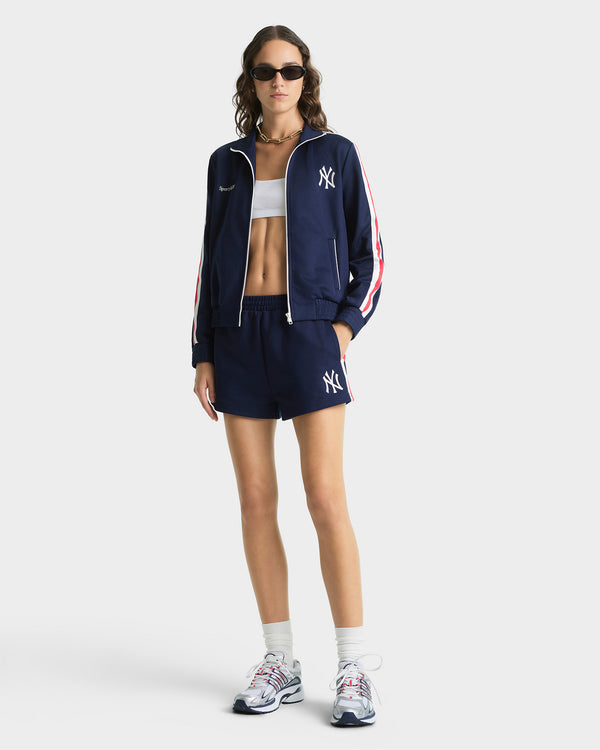 Person wearing a navy tracksuit with white accents on a white background