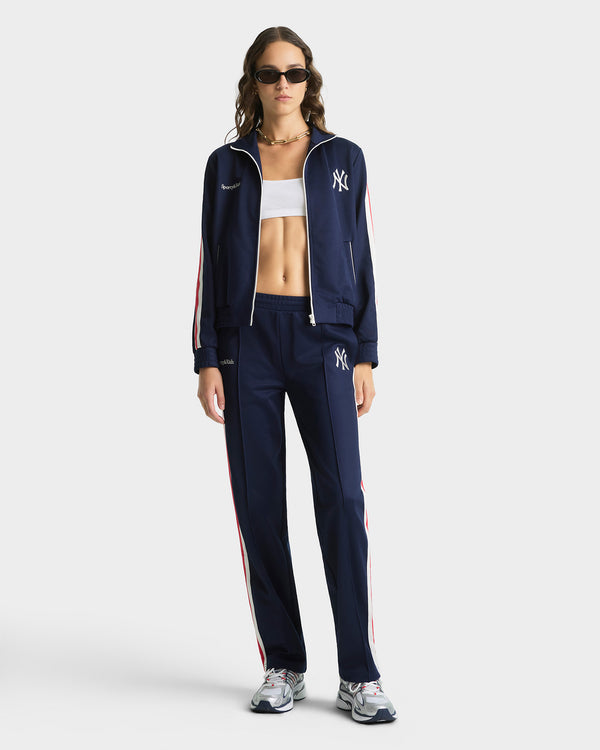 Woman wearing a navy tracksuit with a sports brand logo on a white background