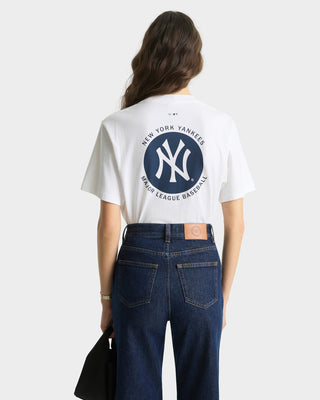 Person wearing a New York Yankees t-shirt with a logo on the back, standing against a white background.