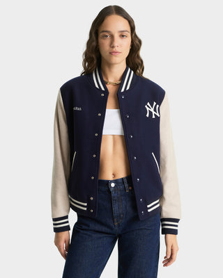 Person wearing a navy and beige varsity jacket with a logo on a white background