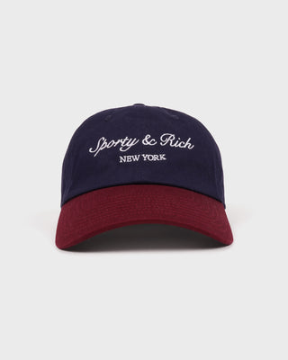 Navy and red cap with 'Sporty & Rich New York' text on a light gray background