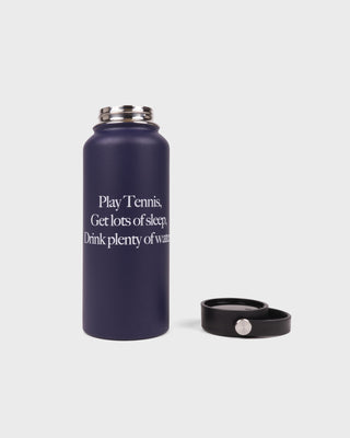 Navy blue water bottle with motivational text and black bracelet on a light gray background