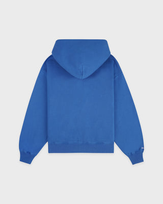 LA Serif Zip Hoodie in Team Blue/White, featuring a white LA logo on the left chest, front pockets, and a zip closure. Crafted from 100% cotton with an oversized fit and displayed laid flat on a white background.