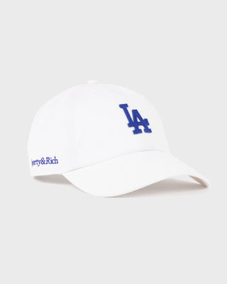 Introducing the LA Hat - White/Team Blue, a white baseball cap featuring a team blue embroidered LA logo on the front, an adjustable closure for a customized fit, and showcased against a plain white background.