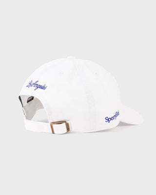Introducing the LA Hat - White/Team Blue, a white baseball cap featuring a team blue embroidered LA logo on the front, an adjustable closure for a customized fit, and showcased against a plain white background.