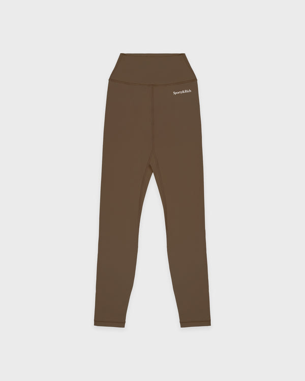Serif Logo Legging - Sand: Classic high-waist, ankle-length leggings in brown (sand) with a small white logo on the waistband, displayed on a white background.