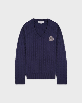 Navy blue cable knit sweater with a logo on a light gray background