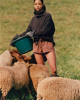 Person standing with sheep in a grassy field