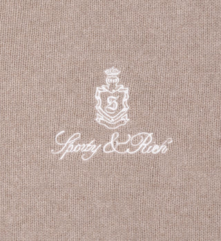 The Vendome Cashmere Short in Oatmeal/White features a beige knit fabric, white embroidered logo with Sporty & Rich script, and a comfortable elastic waistband.