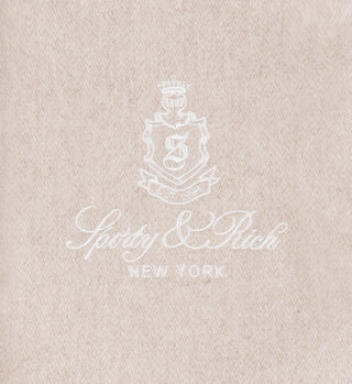The Vendome Wool Varsity Jacket in Oatmeal/Cream features tan fabric with a white embroidered crest above “Sporty & Rich NEW YORK” in script, channeling classic varsity jacket elegance.