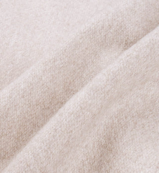 Close-up of soft, light beige wool fabric with gentle folds and a textured surface, highlighting the refined look of the Vendome Wool Varsity Jacket in Oatmeal/Cream.
