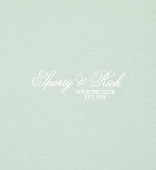 The Villa T-Shirt - Jade/White features light green fabric with white cursive Sporty & Rich Country Club EST. 1994 text, crafted from USA-grown cotton.