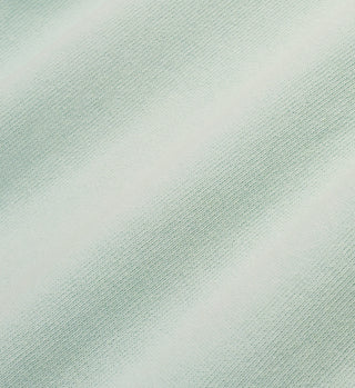 Close-up of Villa T-Shirt - Jade/White, featuring light green USA-grown cotton fabric with a soft feel and subtle diagonal shadow lines.