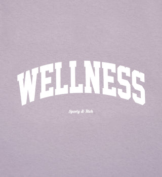 White text on a faded lilac background reads WELLNESS above Sporty & Rich, highlighting our Wellness Ivy T-Shirt - Faded Lilac/White—made in Los Angeles from 100% USA grown cotton.