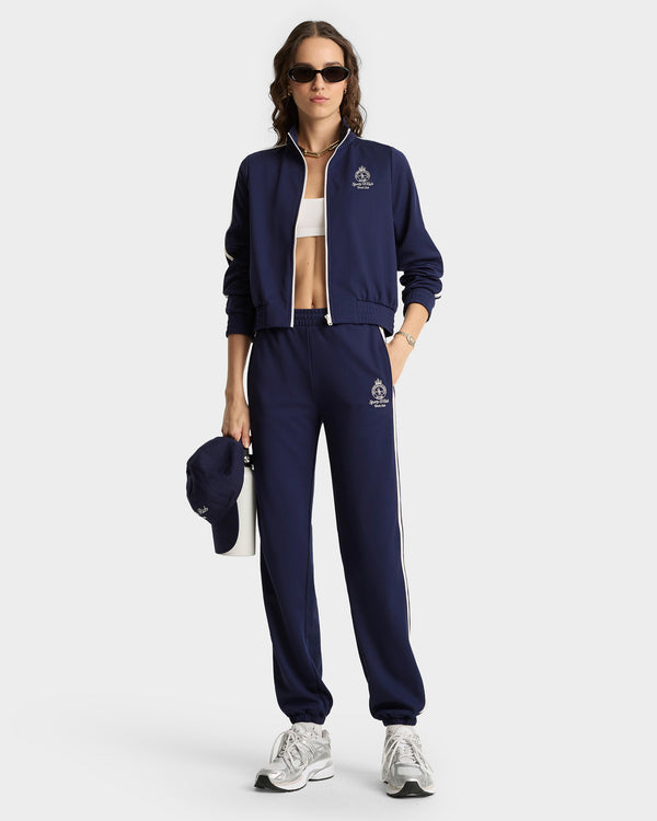 Person wearing a navy tracksuit with a logo on a white background