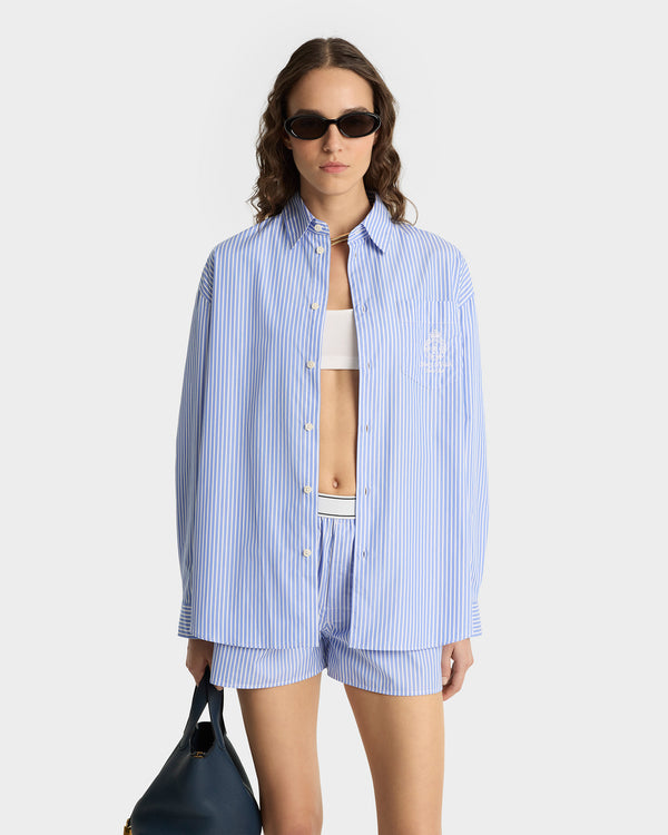 Woman wearing a blue striped shirt and shorts with a white background