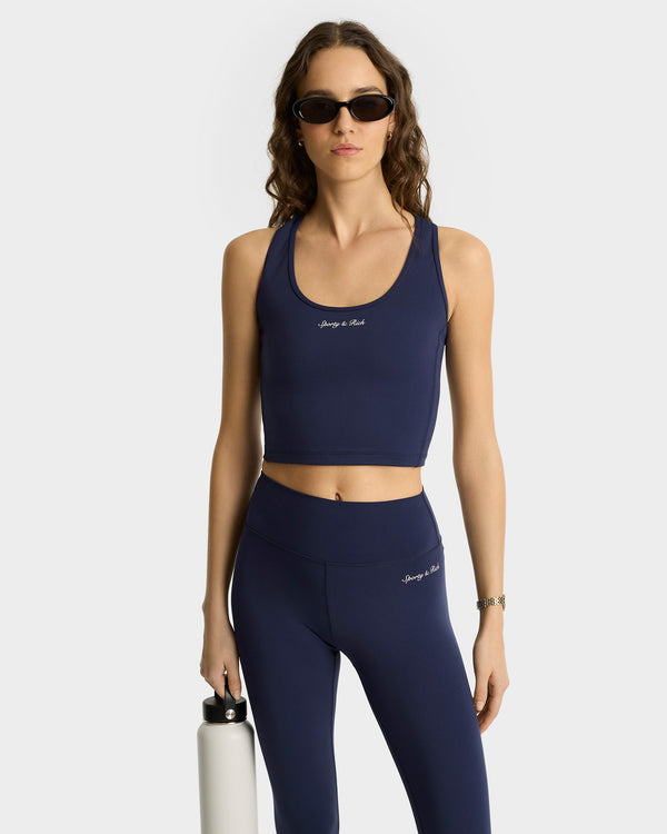 Woman wearing the Syracuse Sports Tank in Navy/White, made from high-quality fabric, holds a white bottle and wears sunglasses against a plain background.