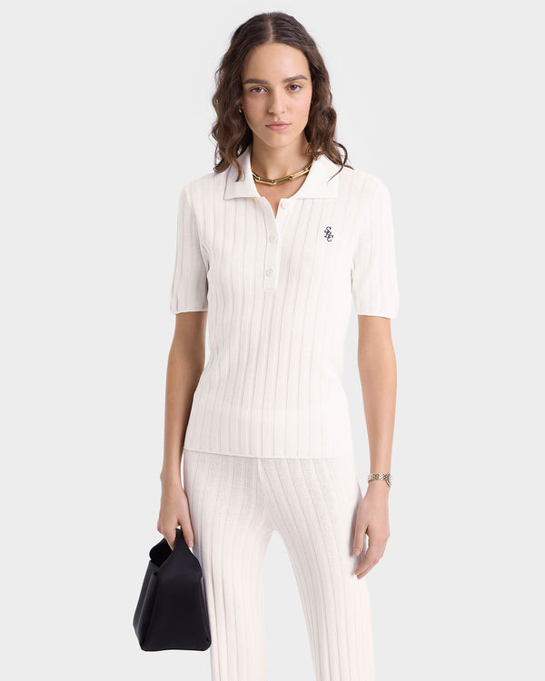 Woman wears the SRC Ribbed Polo in Ecru/Navy, styled with matching pants and a black handbag, standing against a plain background.