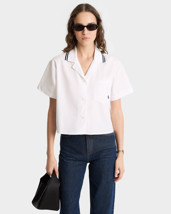 Woman wearing the SRC Sailor Shirt in White/Navy, paired with dark jeans, sunglasses, and a black handbag. This elegant look showcases quality craftsmanship and is expertly made in Portugal.