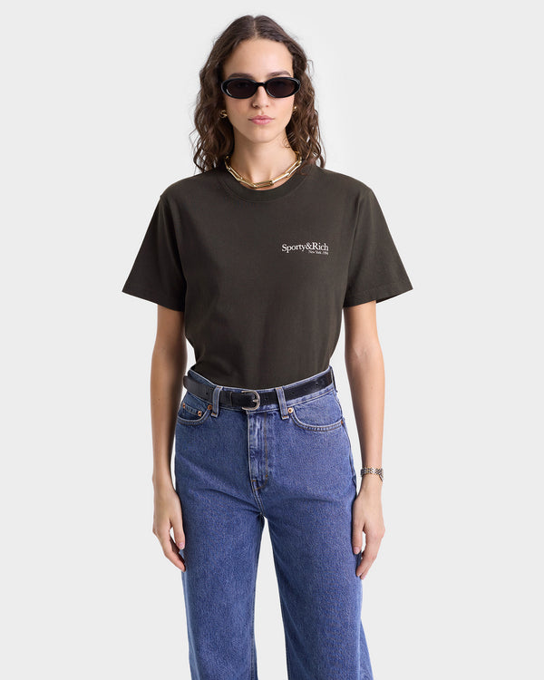 Model wearing faded black T-shirt with white 'Sporty & Rich' text on the left chest, featuring a crew neckline and short sleeves.