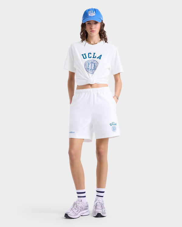 Person wearing a blue UCLA cap, white 100% cotton UCLA t-shirt, UCLA Crest Gym Short - White/Blue, striped socks, and sneakers. Made in Los Angeles.