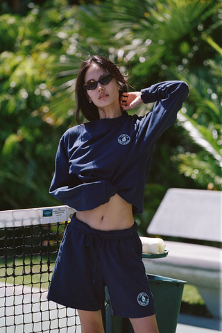 Cadillac x Sporty & Rich Payton Sweatshirt in navy blue, featuring a small white circular logo on the left chest, displayed on a white background.