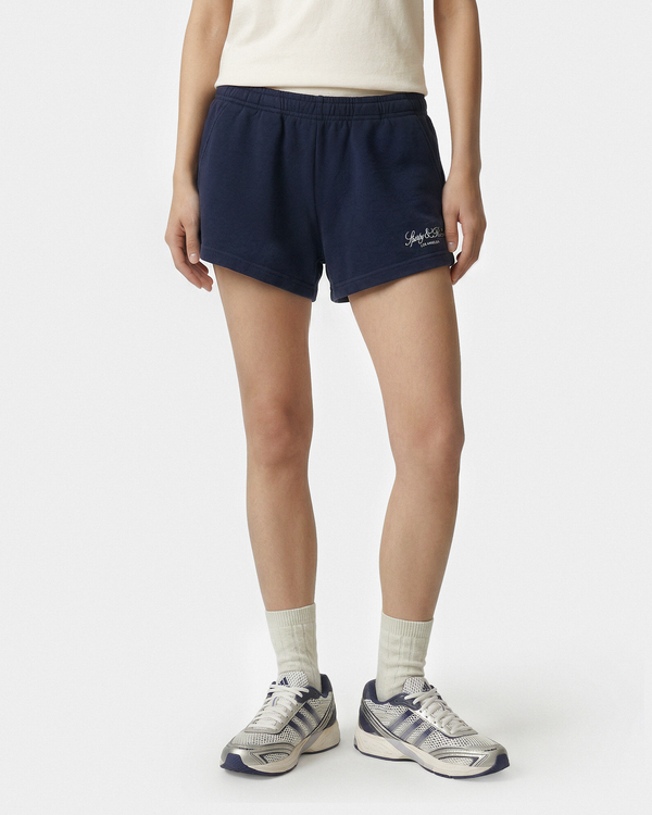 Person wearing navy shorts with a brand logo on a white background