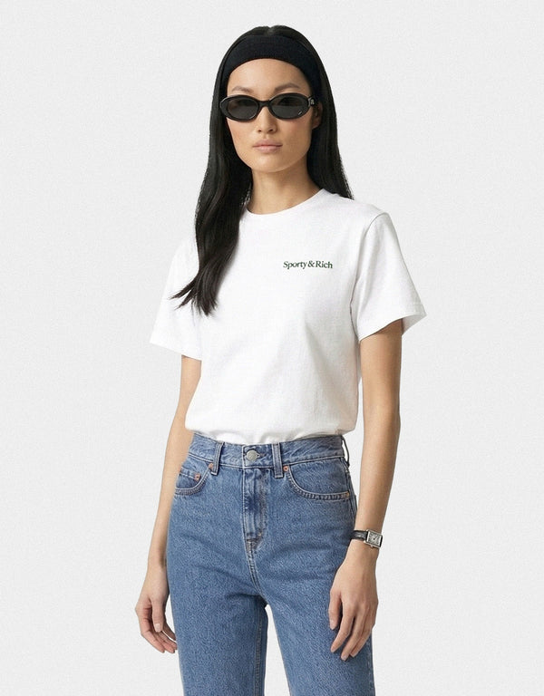 Person wearing a white t-shirt with text and blue jeans on a plain background
