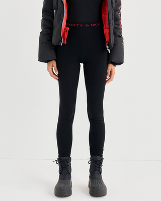 Badir Bold Logo Alpine Legging in black, featuring a high waist, red side stripe, and red text on the waistband.