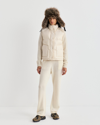 Cream-colored Devano Bold Logo Mountain Puffer Vest for cold-weather training, featuring a high collar and chest logo.