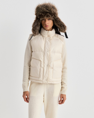 Cream-colored Devano Bold Logo Mountain Puffer Vest for cold-weather training, featuring a high collar and chest logo.