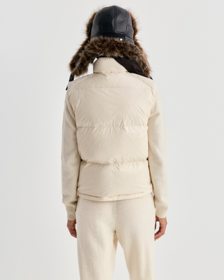 Cream-colored Devano Bold Logo Mountain Puffer Vest for cold-weather training, featuring a high collar and chest logo.