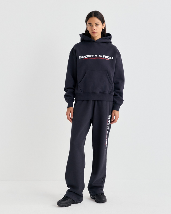 A person in a matching black hoodie and Blakely Bold Health Wide Sweatpant - Black with white lettering.