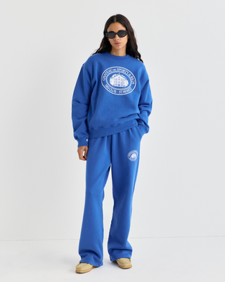 Vibrant blue Emmett Chateau Crewneck with a white circular logo featuring a ski lodge graphic.