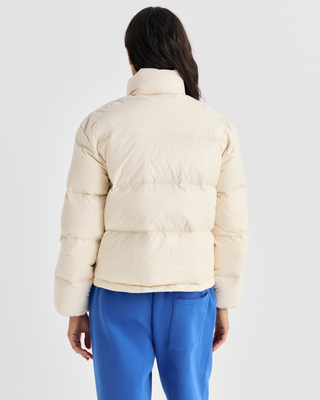 A cream-colored puffer jacket with a stand-up collar and zippered front, displayed on a light gray background.