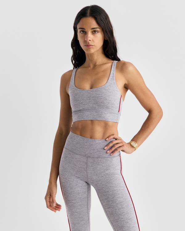 Flor Bold Logo Active Bra in medium heather gray with thin red side stripes and a racerback design.