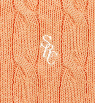 Close-up of the SRC Cotton Cableknit Sweater in Grapefruit, a unisex cotton cableknit with white SPC embroidery at the center. Made in Portugal.