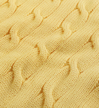 Close-up of SRC Cotton Cableknit Sweater in pale yellow, highlighting its textured twisted knit and subtle embroidered logo.