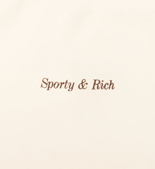 The Classic Logo Cropped Tank - Cream features Sporty & Rich in brown cursive text printed at the center.