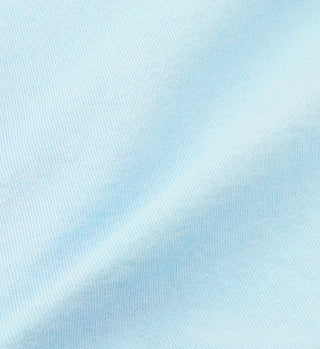 Close-up of baby blue SR Gymnastics T-Shirt fabric, made in USA from 100% cotton, showing a subtle diagonal fold and textured surface.