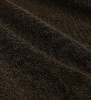 Close-up of dark brown, textured fabric with soft folds and a slightly rough surface—SRC Longsleeve Terry Polo in Chocolate, crafted from 100% cotton terry and made in Portugal.
