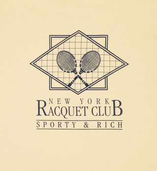 NY Racquet Club T-Shirt - Almond/Navy features two crossed tennis racquets and New York Racquet Club, Sporty & Rich text on a beige background. Made in the USA from 100% USA-grown cotton.