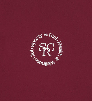 The Sports Bra N.02 - Merlot features a centered, upside-down white Sporty & Rich Health & Wellness Club logo on a Merlot maroon background, combining timeless style with classic athletic inspiration.