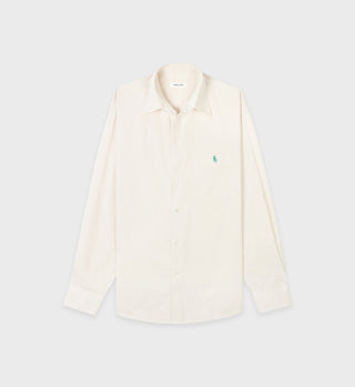 The SRC Oversized Shirt - Cream is a plain cream cotton poplin shirt with long sleeves and a small green logo on the chest pocket, made in Portugal.