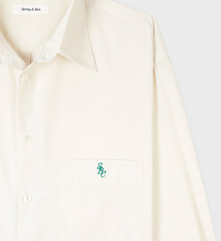 The SRC Oversized Shirt - Cream is a cream-colored cotton poplin shirt featuring an oversized fit, chest pocket, green SRC embroidery, and Sporty & Rich label. Made in Portugal.