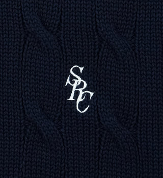 Close-up of the SRC Cotton Cableknit Sweater - Navy, featuring navy blue cotton cableknit fabric and white embroidered SRC letters at the center, highlighting its classic unisex knitwear style.
