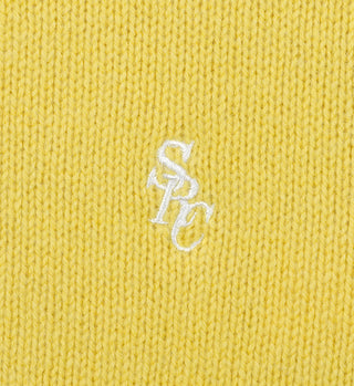 Close-up of the SRC Wool Crewneck - Daffodil, a yellow lambswool knit featuring white embroidered overlapping SPC letters at the center. Made in Italy.