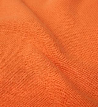 Close-up of the SRC Wool Crewneck in Turmeric, featuring soft orange lambswool with visible knit texture and gentle folds. Made in Italy.